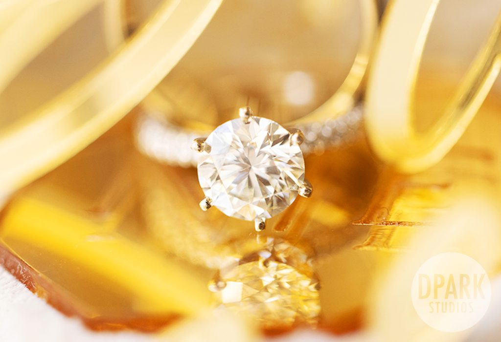 Flatlay of bridal accessories: Miss Dior, heels, gold earrings on lace