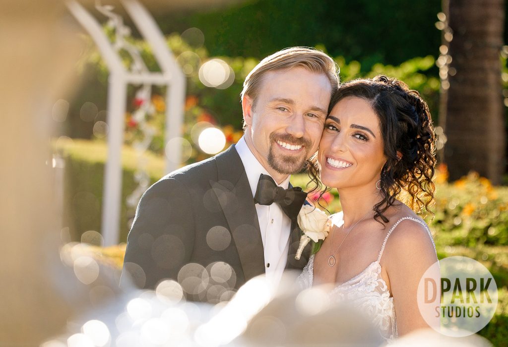 Groom holding bride close under a burgundy floral arch