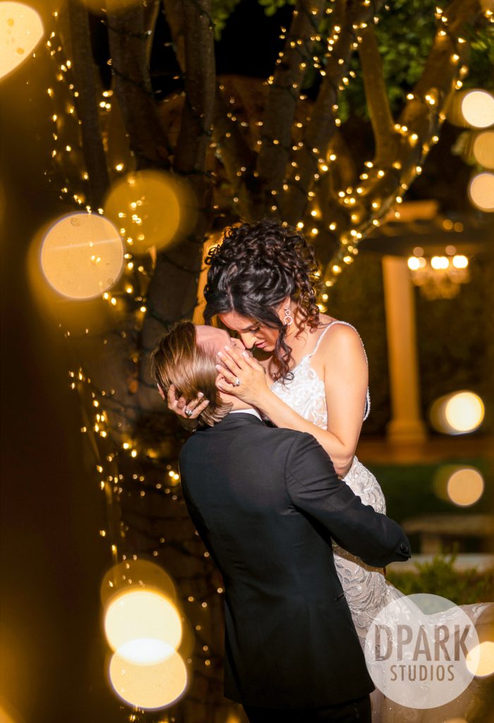 Romantic forehead kiss under Villa De Amore’s twinkle lights