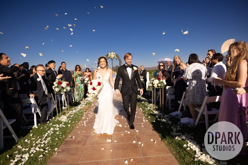 Bride walking down the aisle with white and burgundy bouquet